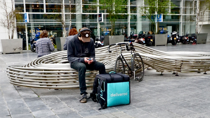 Deliveroo rider waiting on a bench