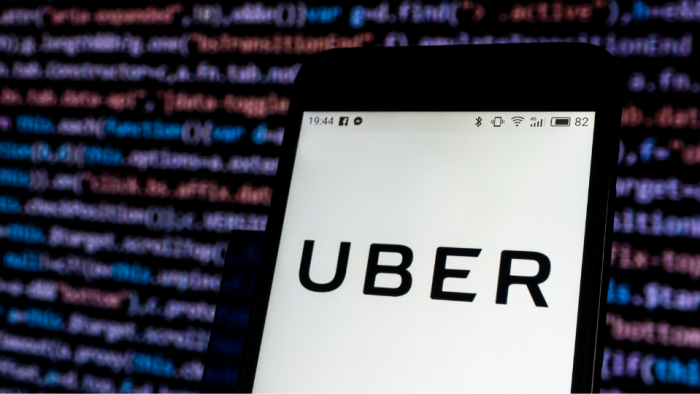 Phone with Uber logo and code lines in the background