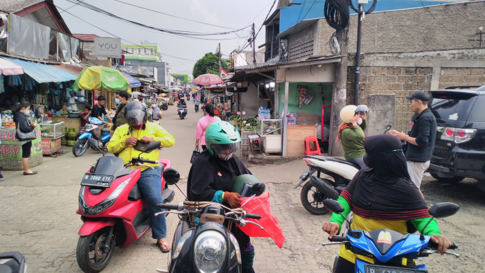 motorbike taxis - photos of women and men on their motorbikes after dropping their passengers off at the Depok train station, with cement-cast streets in the background. Depok city, November 5, 2022